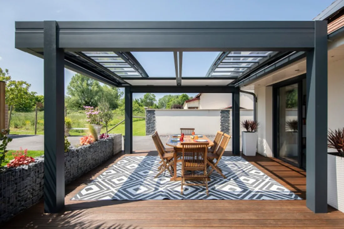 Terrassenüberdachung aus anthrazitfarbenem Metall mit Glasdach über einer Sitzgruppe