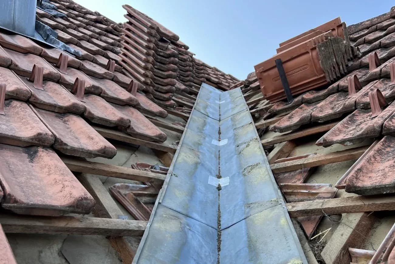Reparatur an einer Dachkehle mit neuer Verblechung und neu gesetzten Ziegeln